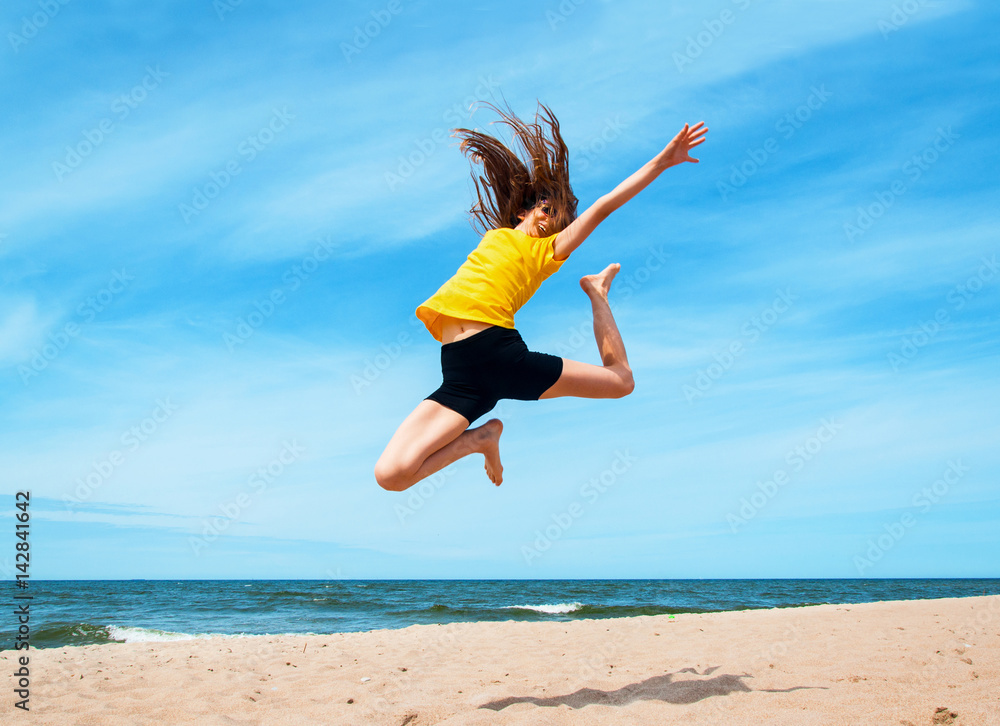 Happy active girl jumping at the beach
