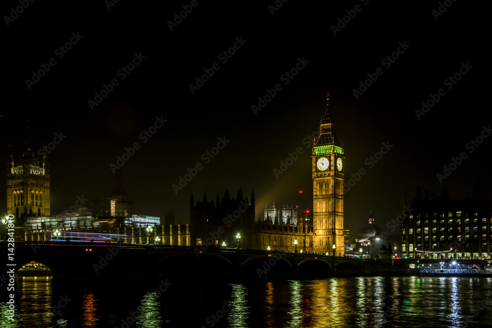 Houses of parliament and Westminster Bridge at night with lights reflected in Thames water , London