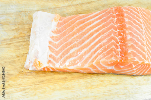 fresh raw uncooked salmon fish piece over wooden board background