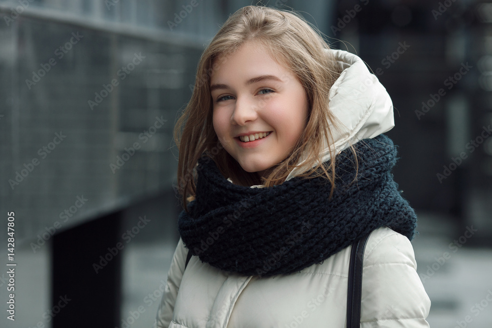City portrait of young beautiful blonde stylish girl posing in spring fall outdoors in white coat black knitted scarf. Vintage filter film saturated colors. Emotion demonstration concept. City portrait of young beautiful blonde stylish girl posing in spring fall outdoors in white coat black knitted scarf. Vintage filter film saturated colors. Emotion demonstration concept.