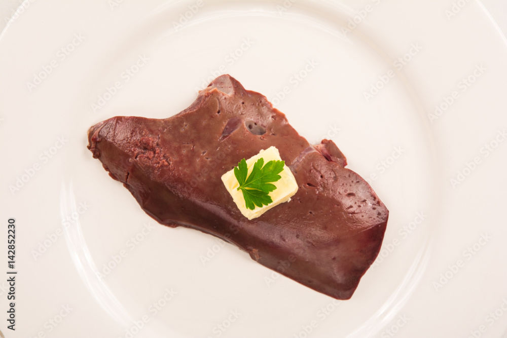 high angle view of a raw veal liver isolated on white plate with butter and parsley high angle view of a raw veal liver isolated on white plate with butter and parsley