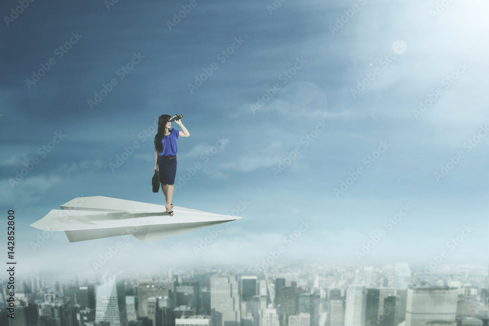 Young businesswoman flying with paper plane