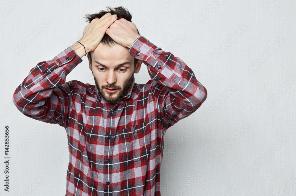 Young Caucasian man with beard in despair covers his head with hands. Worry due to problems and stress. Missed opportunities due to poor memory. Human emotion concept. Young Caucasian man with beard in despair covers his head with hands. Worry due to problems and stress. Missed opportunities due to poor memory. Human emotion concept.