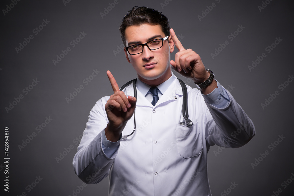 Fototapeta premium Young doctor against dark background