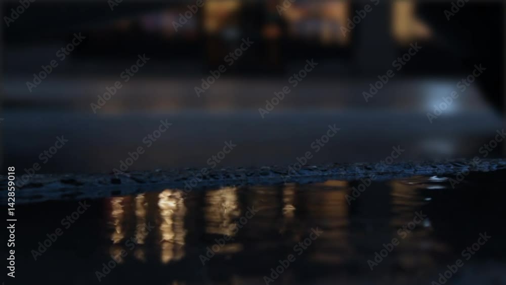 Puddle forming on rainy day in downtown city area with blurry traffic Puddle forming on rainy day in downtown city area with blurry traffic