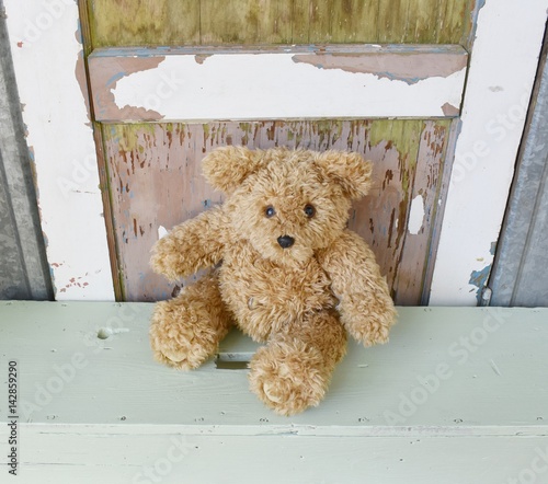 Child's teddy bear toy sitting on a bench.