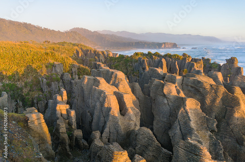 Sunlit cliffs, rocks and ocean coastline landscape photo