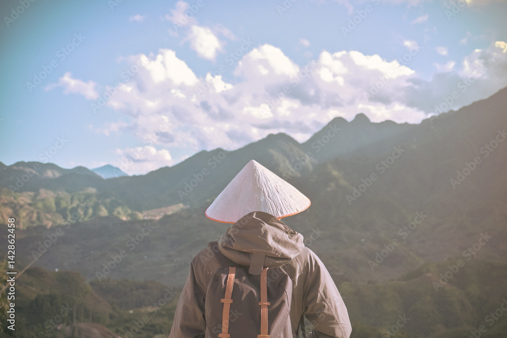 Alone traveler with Nonla hat at peak mountain background, Sapa Vietnam, travel concept.