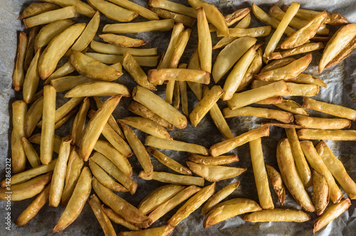 Baking tray full of homemade potato fries straight out of the oven