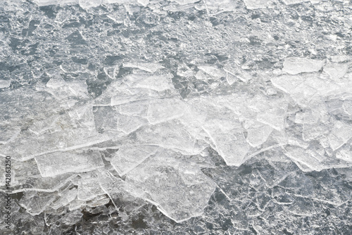 Abstract background of shards of broken ice glittering in the sun on the ice on a frozen lake