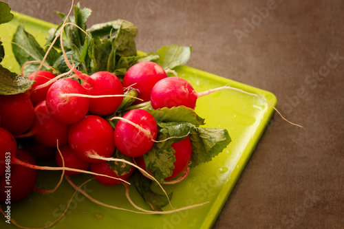 Vászonkép Fresh Radishes on a cutting board on a textured background