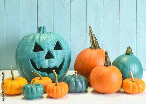 Teal and orange pumpkins in a Halloween still life indicating that both allergy safe non food treats as well as candies are available to trick and treaters