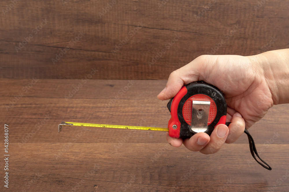 Tape measure on wooden background.