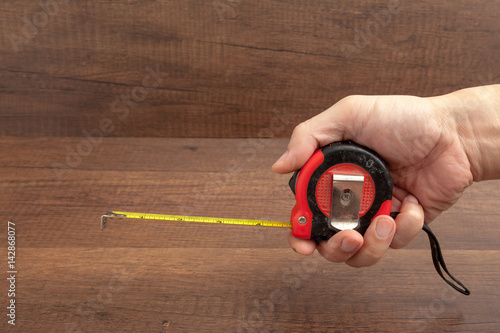 Tape measure on wooden background.