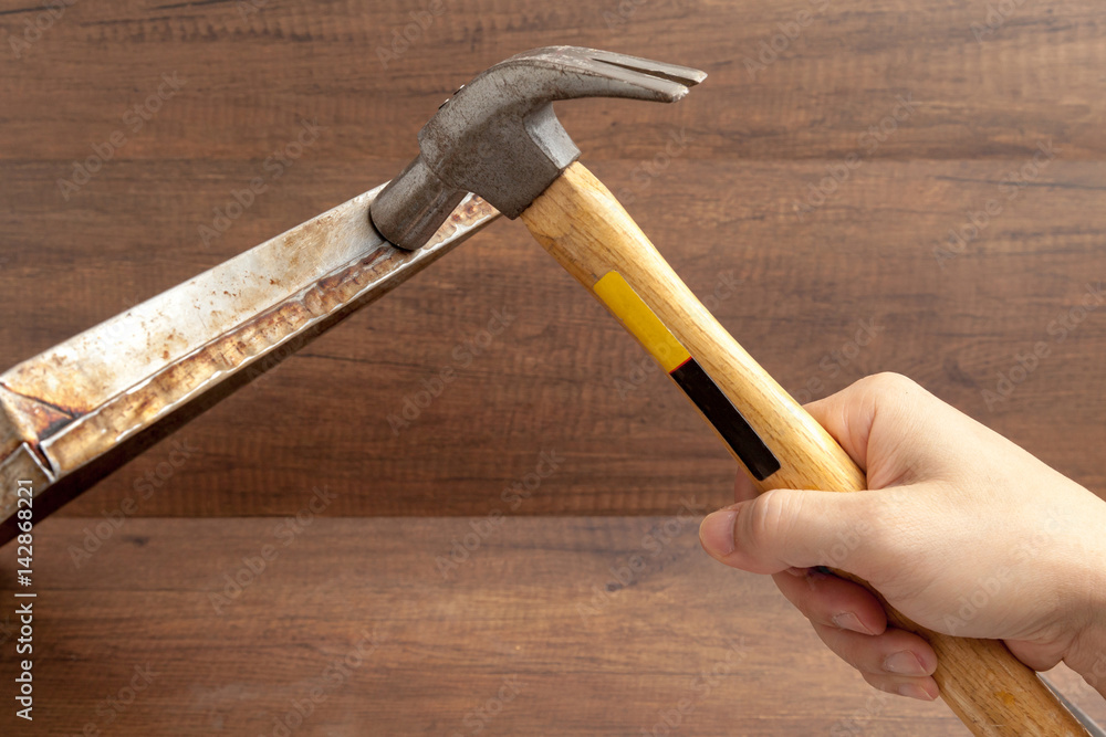 Man handle hammer to hit or fix stainless tray on wooden background.