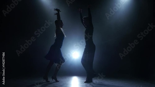 Professional couple of rumba dancers posing in smoky studio, silhouette
