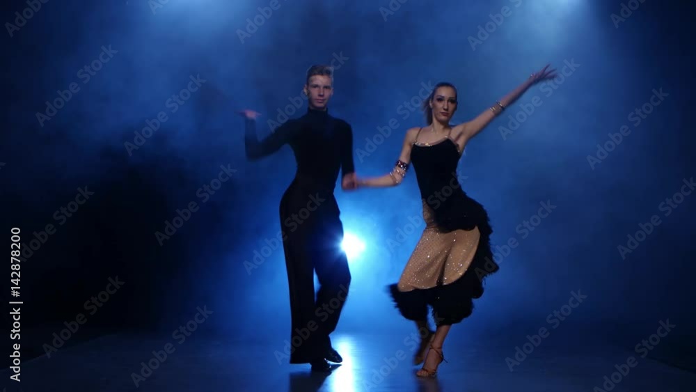 Happy couple dancing jive in smoky studio with blue spotlight Happy couple dancing jive in smoky studio with blue spotlight