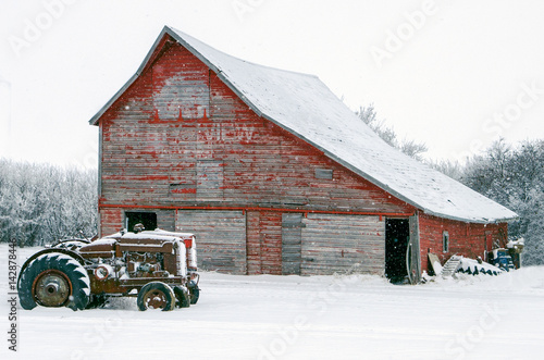 Vintage tractors in front of an old red barn in snow
