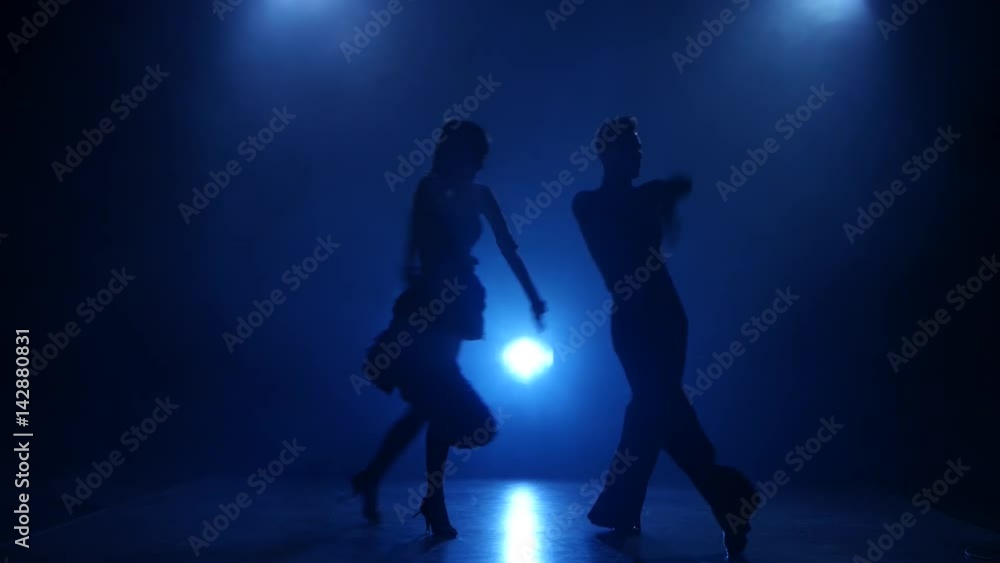 Silhouette of pair dancers performing latino dance in smoky studio Silhouette of pair dancers performing latino dance in smoky studio