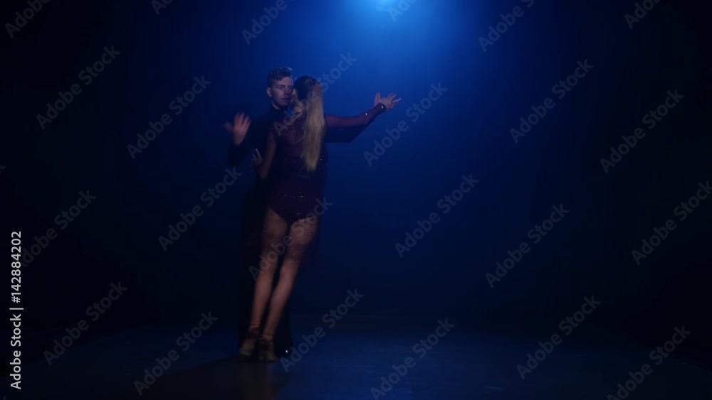 Salsa dancing couple of professional elegant dancers on blue background Salsa dancing couple of professional elegant dancers on blue background