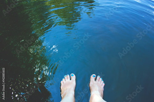 summer background with blue water and women's feet