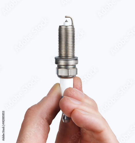 Mechanic holds a spare part spark plug in his hand. Auto part spark plug close-up on a white background.