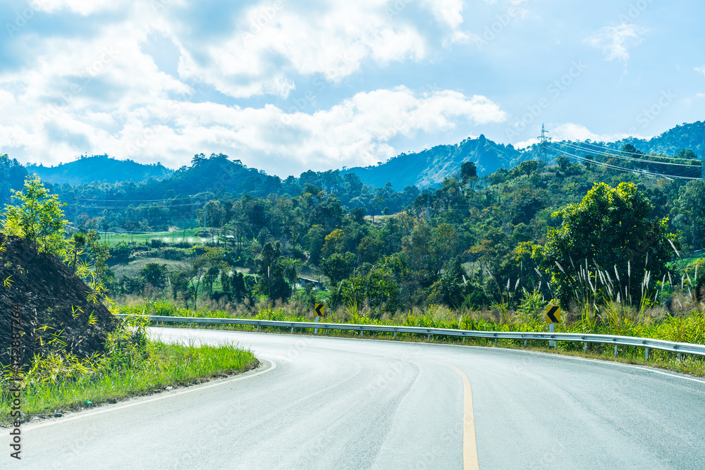 The road through the mountains and forest in the sunlight. The road through the mountains and forest in the sunlight.