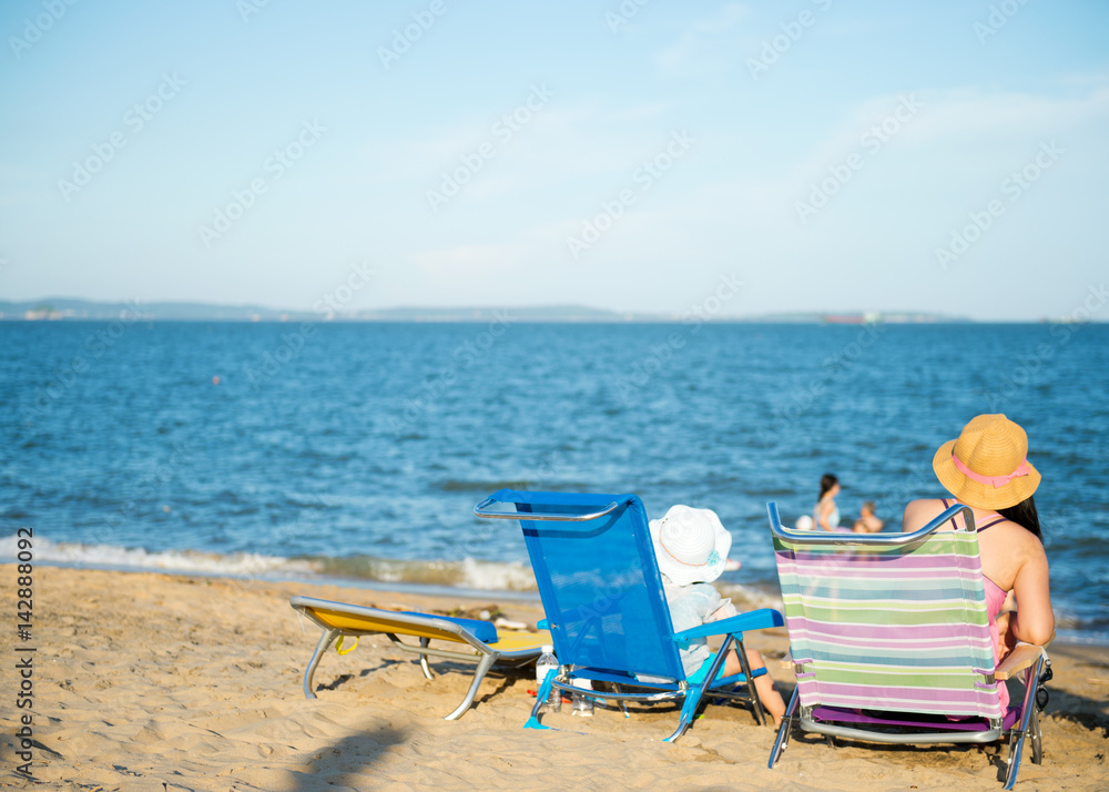 Young mother with baby daughter sitting in front of the sea. Young mother with baby daughter sitting in front of the sea.