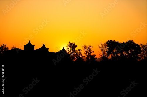 The sun falls in the evening over the house in the garden.