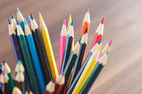 Set of colored pencils in the glass, wooden background
