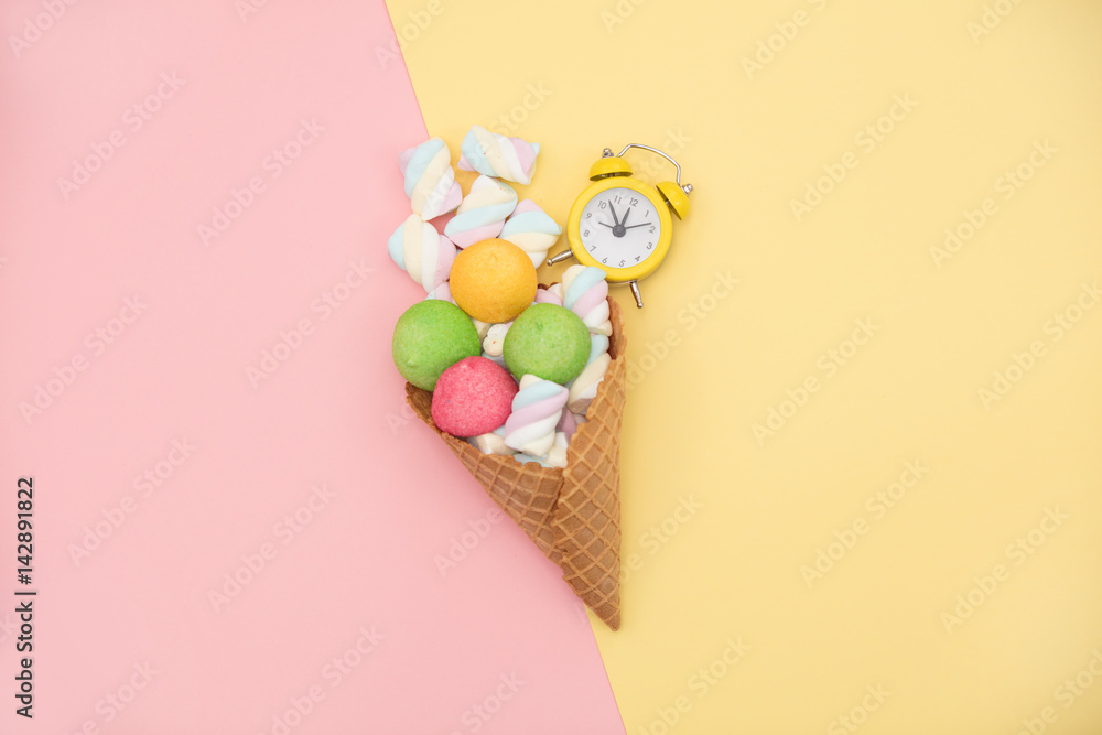 photo of tasty colorful marshmallows in waffle cone and alarm clock on the wonderful colorful background in pop art style