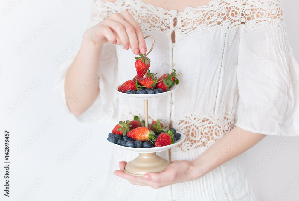 photo of young woman holding stand with fresh berries on the wonderful white background photo of young woman holding stand with fresh berries on the wonderful white background