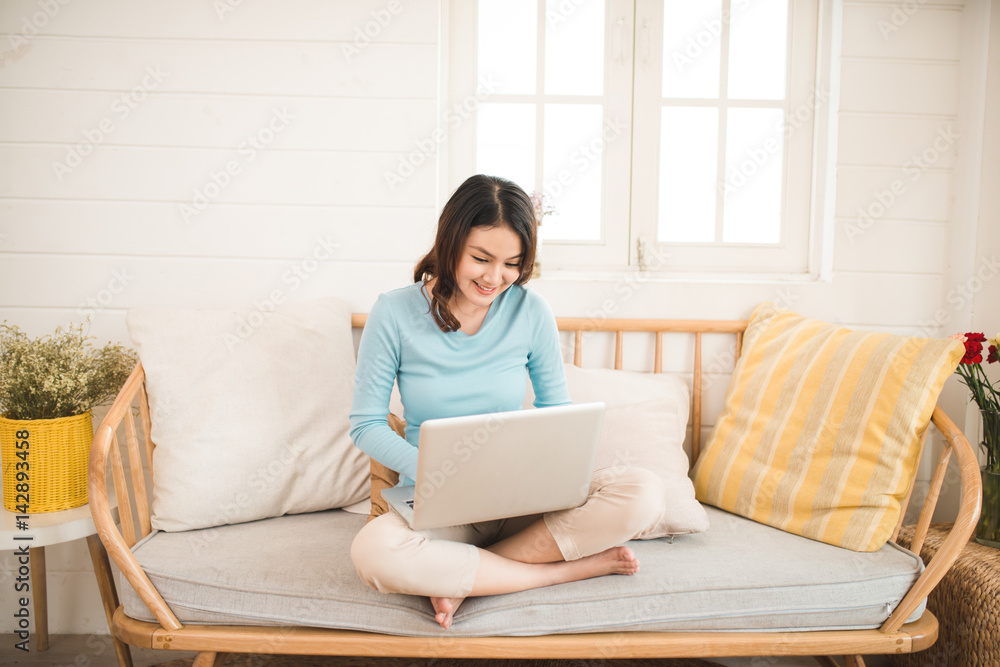 Happy casual beautiful asian young woman working on a laptop at home. Happy casual beautiful asian young woman working on a laptop at home.