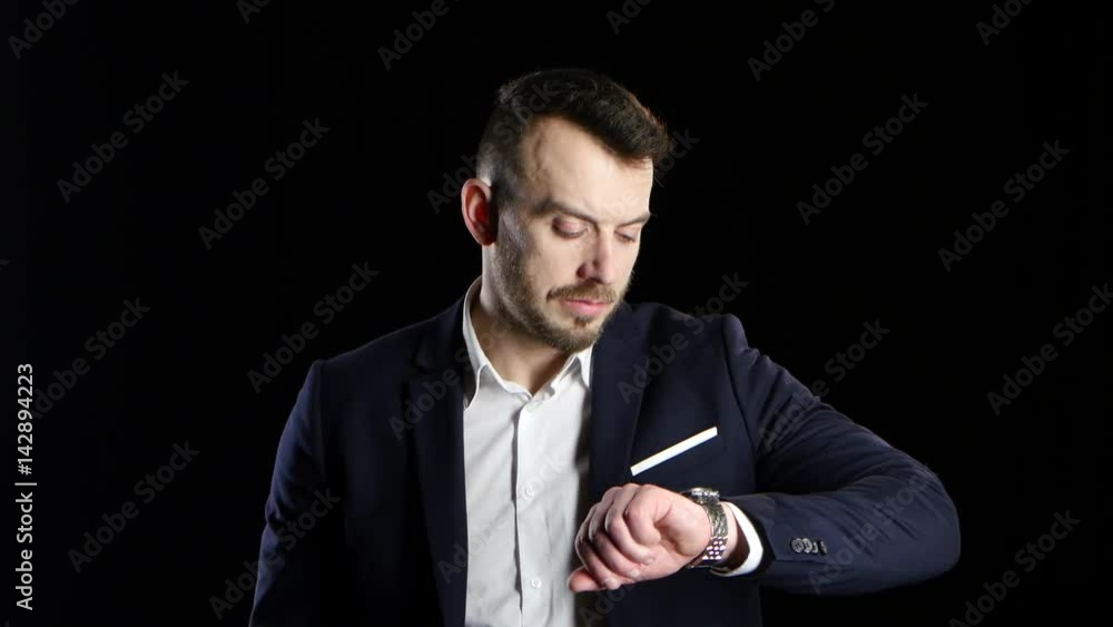 Businessman nervously waits and looks at his watch. Black background Businessman nervously waits and looks at his watch. Black background