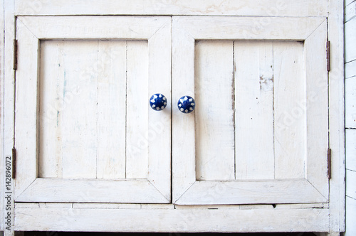 White vintage wooden cupboard with blue knobs