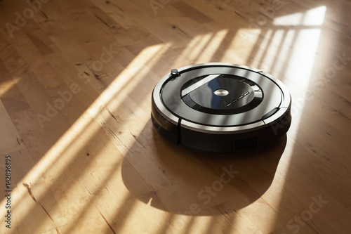 Fotografie robotic vacuum cleaner on laminate wood floor smart cleaning technology