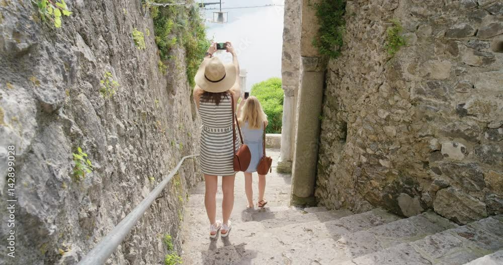Tourist women taking photo exploring old town Girl using mobile phone photographing Italian street Best friends travelling enjoying summer vacation travel adventure in Ravello Amalfi Italy Tourist women taking photo exploring old town Girl using mobile phone photographing Italian street Best friends travelling enjoying summer vacation travel adventure in Ravello Amalfi Italy
