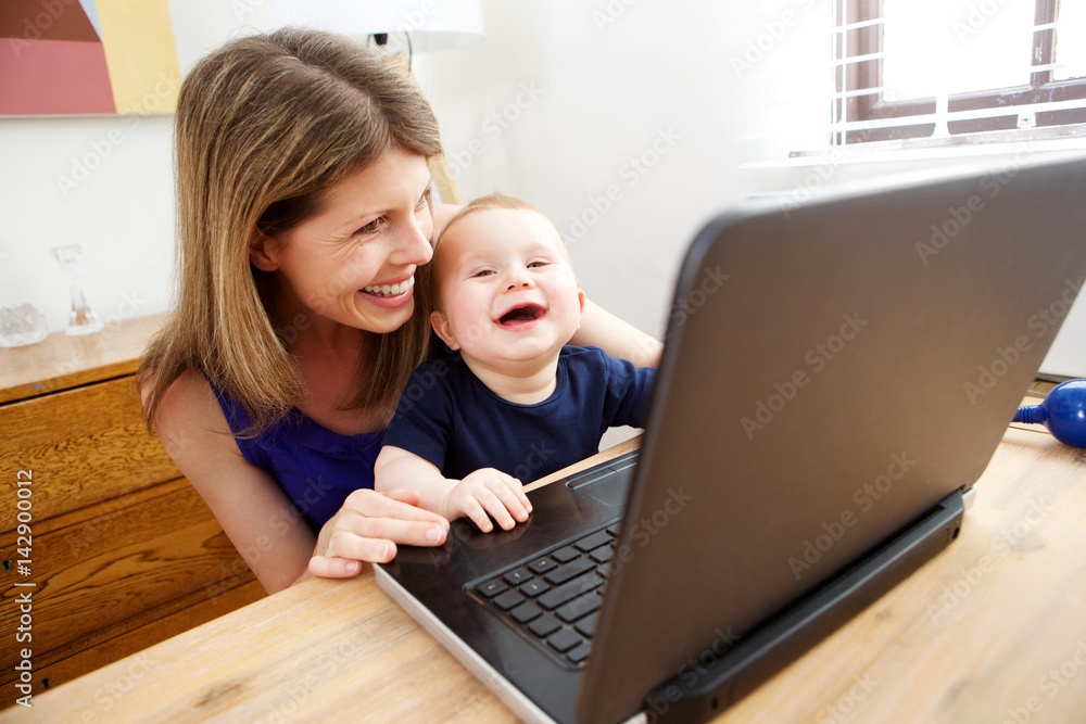 happy mother and baby using laptop and smiling happy mother and baby using laptop and smiling