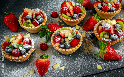 Canvastavla Berry tartlets with blueberries, raspberries, kiwi, strawberries, almond flakes in icing sugar