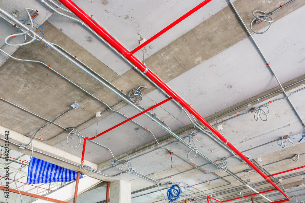 Ventilation pipes in black insulation material and fire sprinkler on red  pipe are hanging from the ceiling inside new building. Stock-Foto | Adobe  Stock