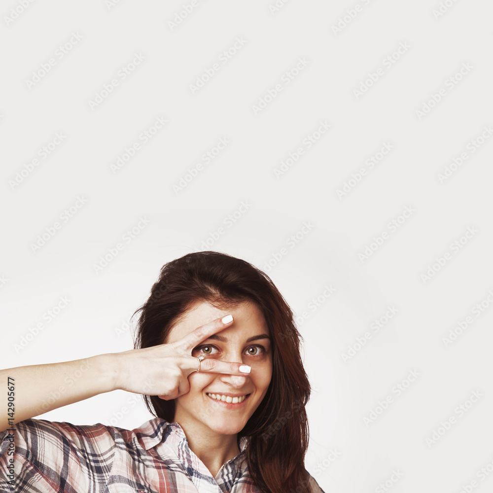 Young woman peeking through fingers Young woman peeking through fingers