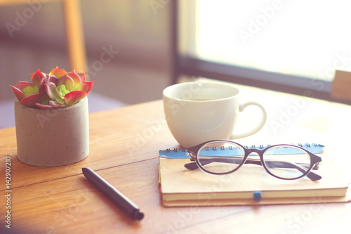 glasses,book,cup coffee,pen,on wood table
