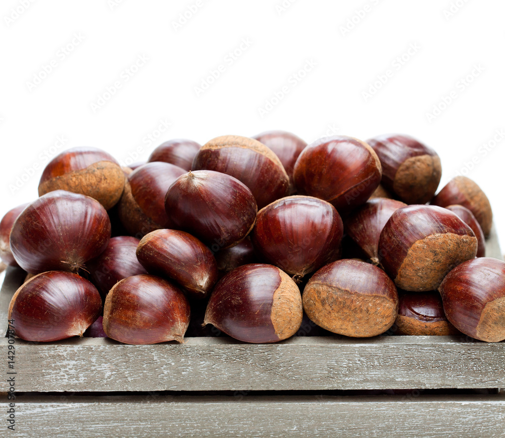 fresh raw chestnuts in a wooden box isolated on white background fresh raw chestnuts in a wooden box isolated on white background