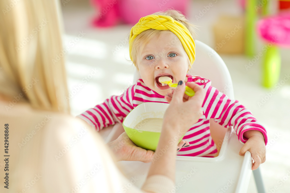 A woman is feeding a young child A woman is feeding a young child