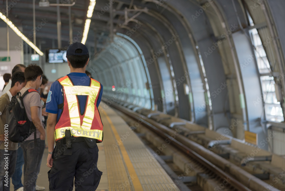 Fototapeta premium Passengers Waiting for train and security man is working at railway station, train station, Railway train on the railroad.Bangkok. Thailand.