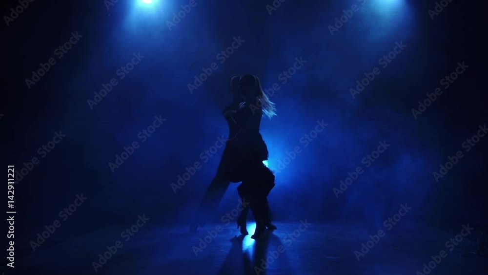 Silhouette of pair dancers performing tango dance in slow motion