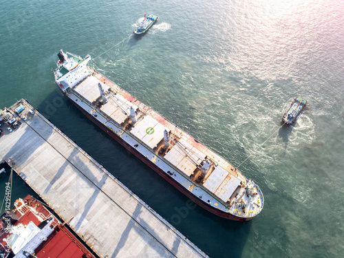 ship on un-berthing the wharf terminal to sailing departure from the port in aerial view photo