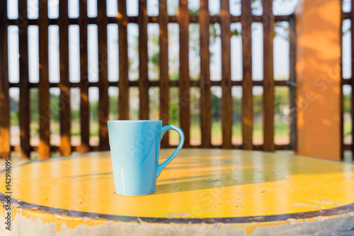 Blue mug on yellow table, Coffee cup front view