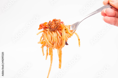 Spaghetti bolognese on a fork held by a hand