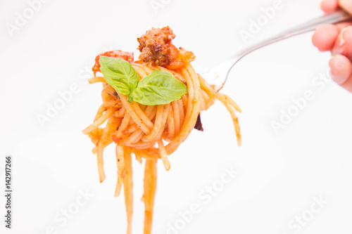 Spaghetti bolognese on a fork held by a hand